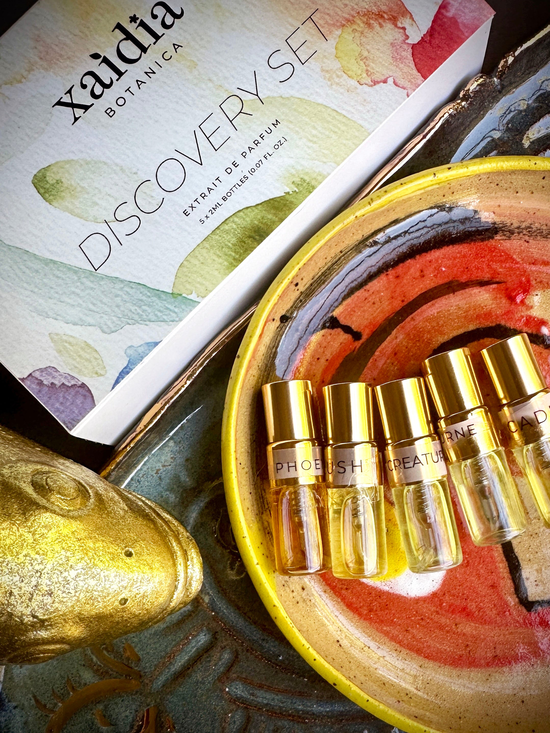 Xaidia Botanica discovery set with gold bottles on a decorative plate, by Micah Riot